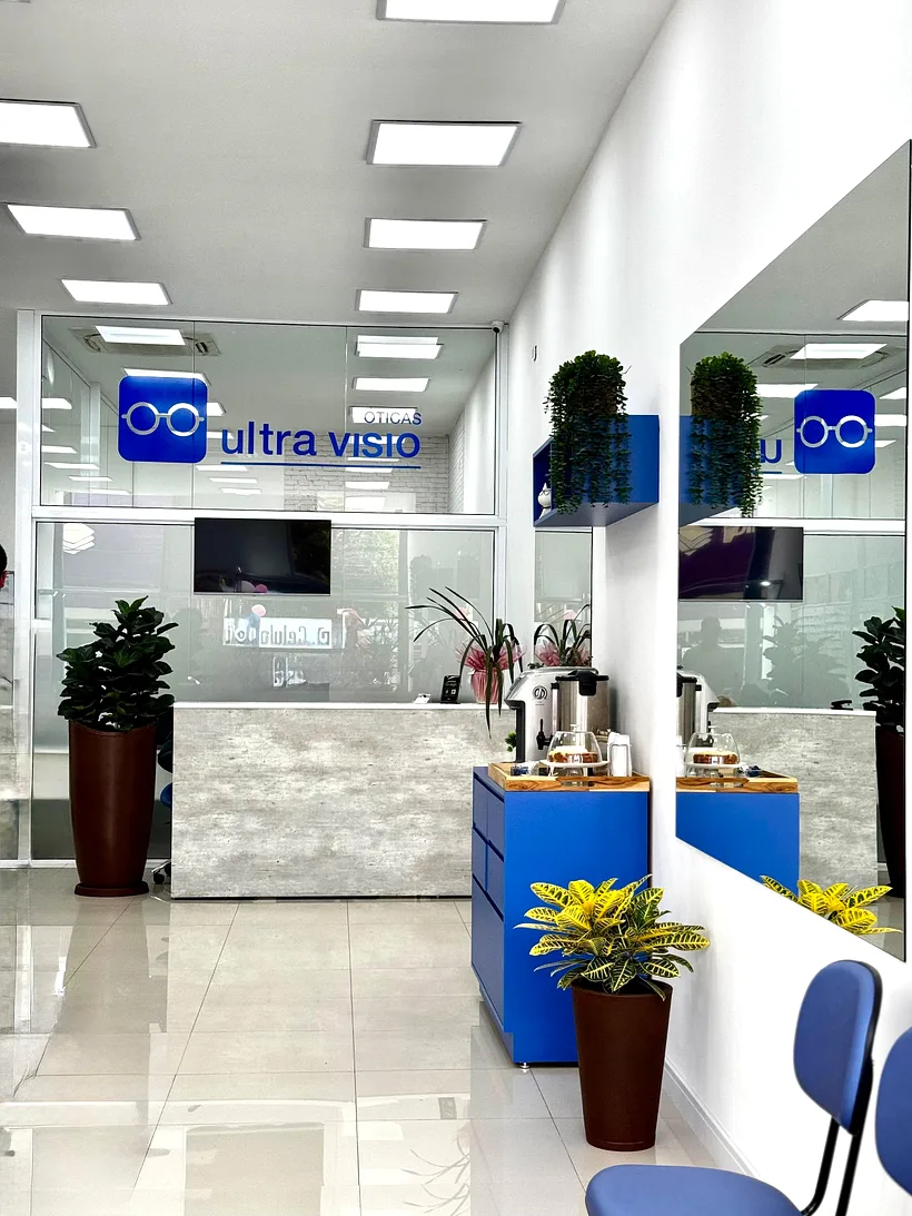 Recepção da Óticas Ultra Visio com estação de café de cortesia e o logo da loja no vidro